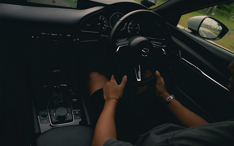 Driver holding a steering wheel inside a modern car interior.