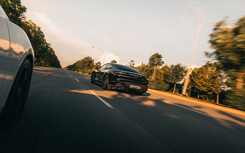 Luxury sports car driving down an empty highway at sunset.