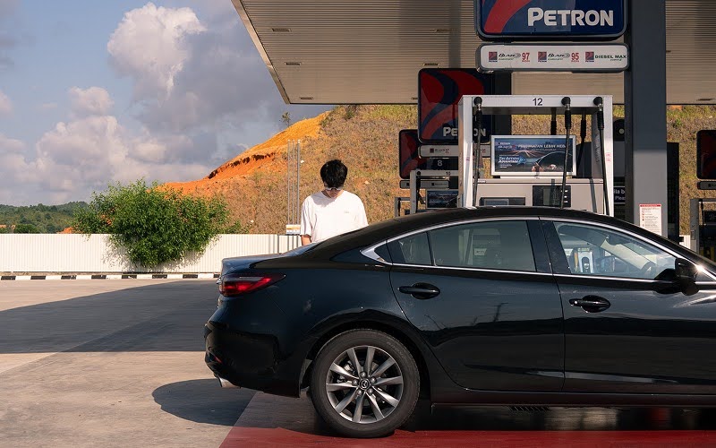 Man refueling car at petrol station amid rising prices.