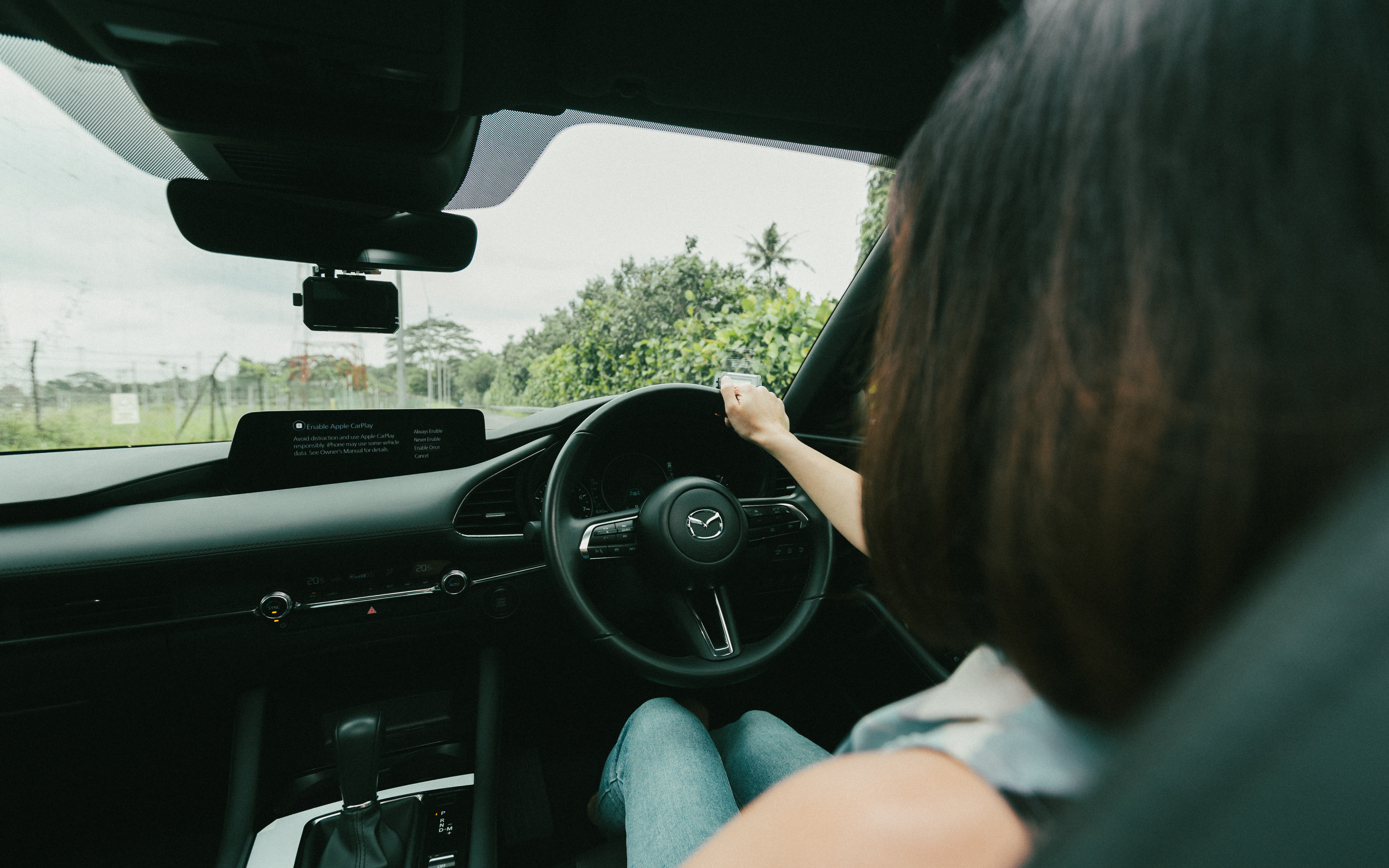 Driver steering a vehicle while planning a trip to Johor.